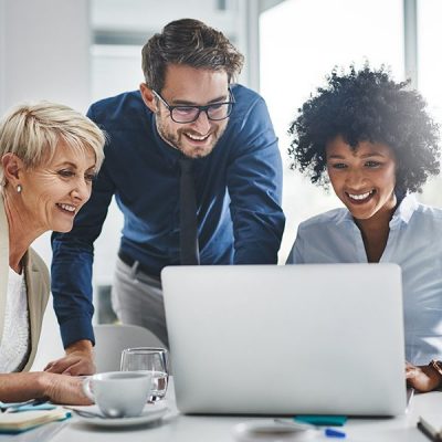 Three employees looking at a laptop